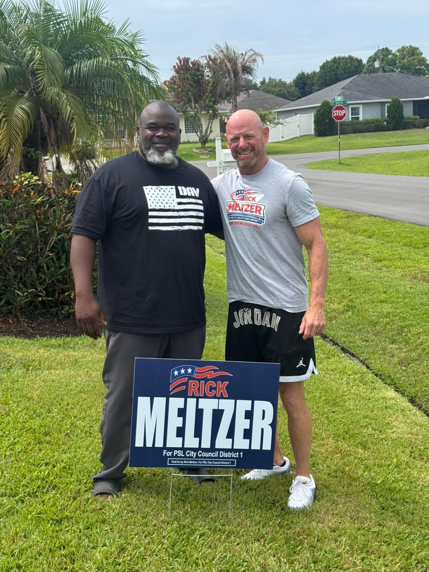 Rick Meltzer meeting a neighbor beside a yard sign
